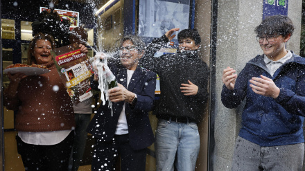 Varias personas celebran a las puertas de la administración de loterías del número 10 de la calle Barquillo