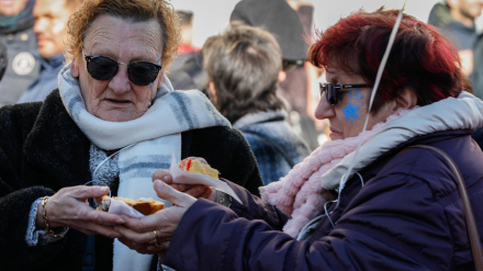 Dos mujeres comen roscón de reyes en un plaza