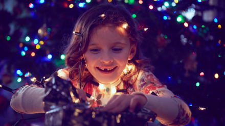 J0C5H9 Girl surrounded by lights wrapping christmas presents at christmas
