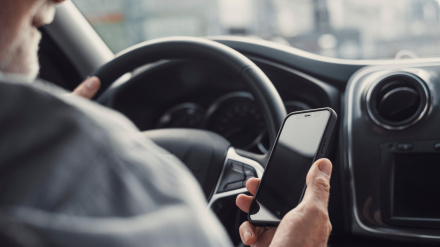 Hombre mirando el teléfono móvil mientras conduce un coche