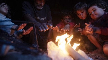 Miembros de una familia palestina desplazada se calientan junto a un fuego fuera de su refugio en la ciudad de Khan Younis, en el sur de la Franja de Gaza.
