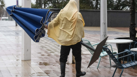 Un hostelero recoge la terraza para protegerse de la lluvia