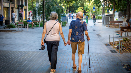 Pareja de jubilados tomados de la mano y caminando juntos por la acera en Barcelona