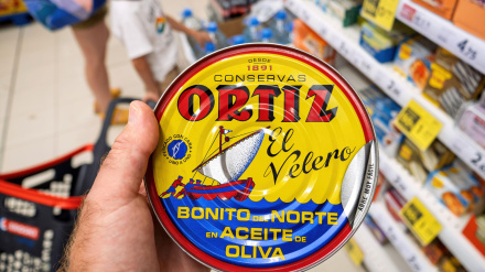 Una mano sostiene una lata de atún Ortiz amarilla con la etiqueta Bonito del Norte en Aceite de Oliva en el pasillo de un supermercado en Mallorca