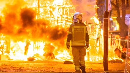 Firefighter with his protective suit working controlling the burning of a Falla during the Valencian fiestas.