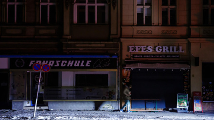 Una persona iluminada por los faros de un coche ante edificios a oscuras durante un apagón en el suroeste de Berlín