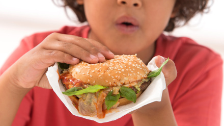 Niño obeso y con sobrepeso comiendo una hamburguesa