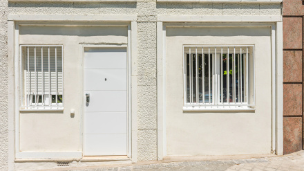 Apartamento tipo loft en planta baja comercial reconvertida con puerta antigua de roble y toldo metálico que marca el acceso a la calle.