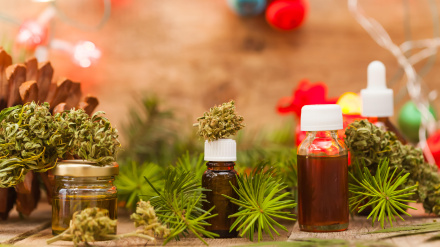 Hojas verdes de cannabis medicinal con aceite extracto sobre una mesa de madera.