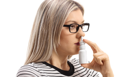 MC6E8B Young woman using a nose spray isolated on white background