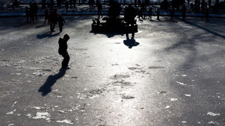 Niños jugando sobre la superficie de una fuente helada.