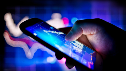 Una persona que usa un teléfono móvil para realizar un seguimiento de los datos bursátiles en tiempo real.