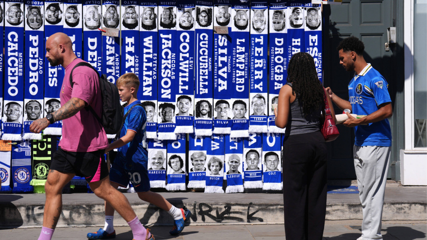 Aficionados del Chelsea pasan junto a un puesto de bufandas en el exterior de Stamford Bridge.