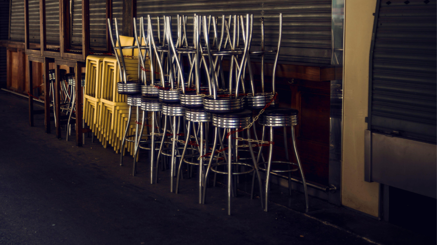 Sillas apiladas frente a una barra cerrada
