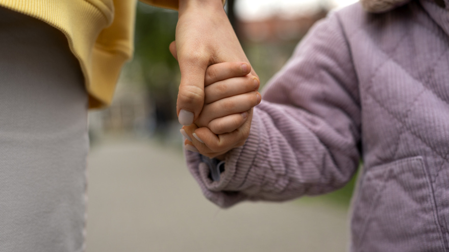 Una madre lleva de la mano a su hija pequeña