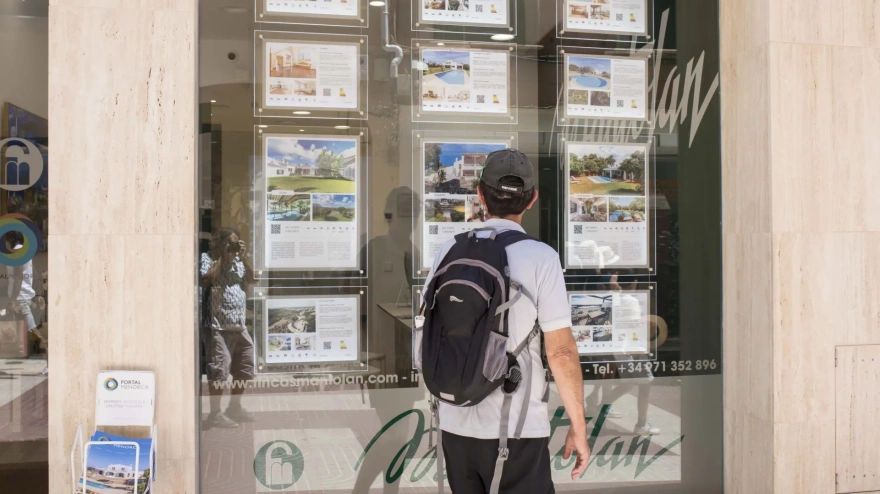 Un joven observa carteles de viviendas en venta