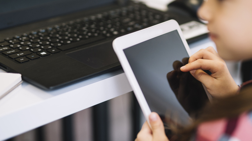 Un niño con una tablet y ante un ordenador portátil