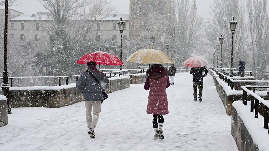 Varias personas caminan entre la nieve caída este miércoles en León. El temporal está dejando o intensas nevadas en la provincia de León