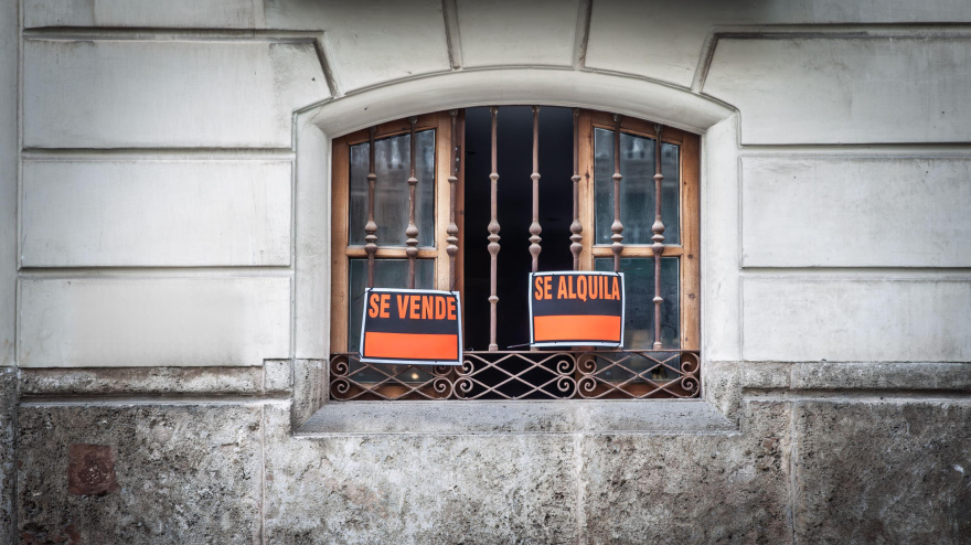 Carteles inmobiliarios de "se vende" y "se alquila" en la ventana de un edificio en Valencia