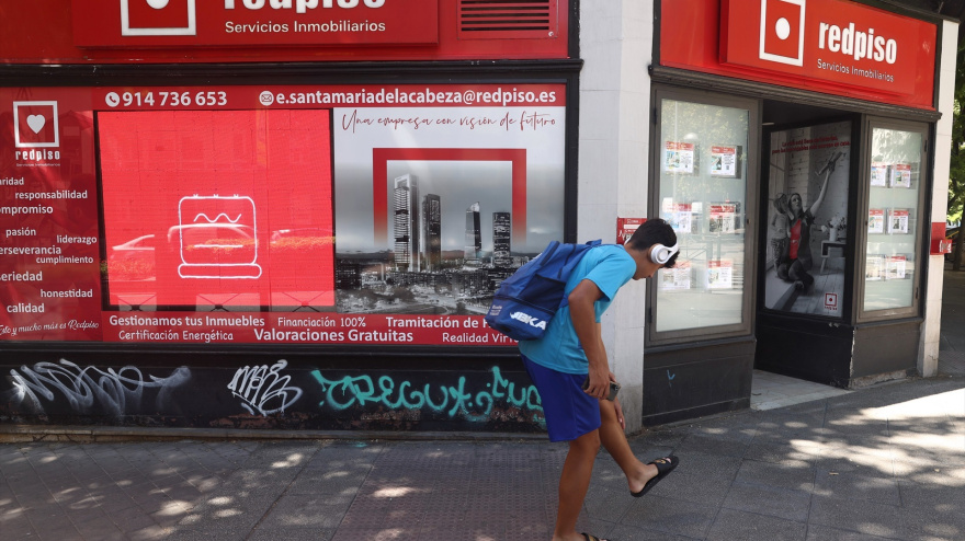 Un joven pasa por una oficina de redpiso con ofertas de pisos del alquiler