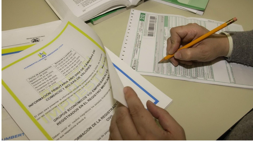 Un hombre firma un formulario para el pago de un impuesto