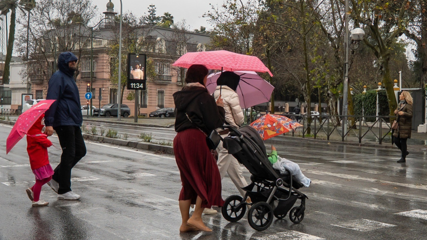 Padres con niños pasean por la calle en Sevilla en un día con clases presenciales suspendidas por la borrasca Leonardo.