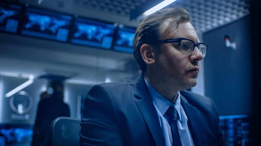 Especialista preocupado trabajando en la computadora en la sala de control de monitoreo con equipos resolviendo problemas en segundo plano