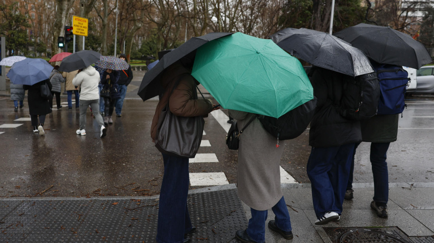 Varias personas se protegen de la lluvia en Madrid
