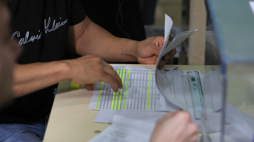 Un miembro de una mesa electoral revisa el censo de votantes en un colegio electoral este domingo en Zaragoza