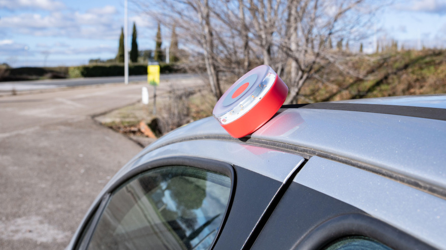 Baliza de emergencia V16 en el techo de un vehículo detenido en la cuneta. Esta señal luminosa forma parte del sistema de seguridad obligatorio implementado en España.