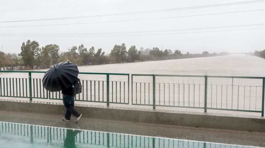Una persona cruza por el Puente de la Señorita cortado al tráfico por el desbordamiento parcial del río Guadalquivir a su paso por la Cartuja