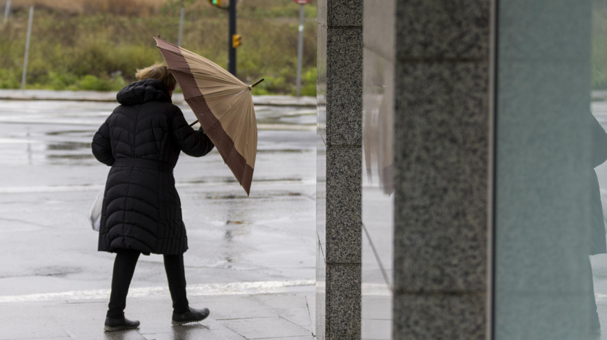 Una mujer se protege del viento y la lluvia en Huelva