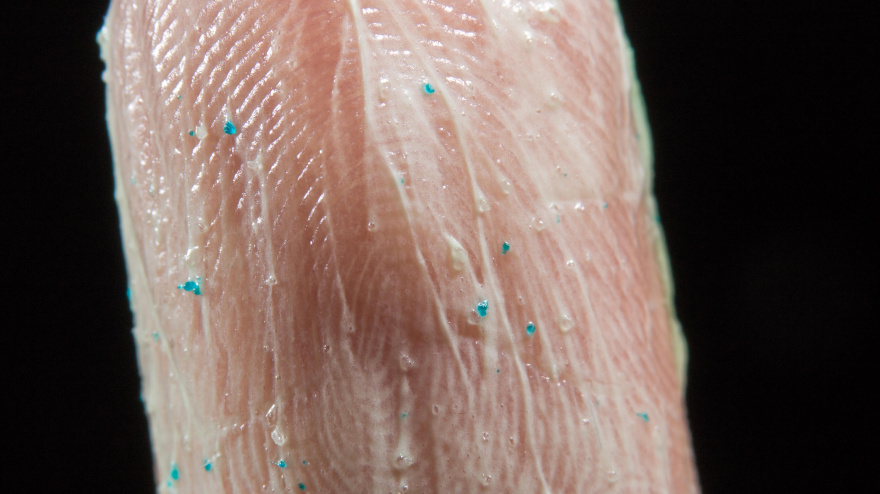 Primer plano de microperlas de un exfoliante facial en la punta de un dedo