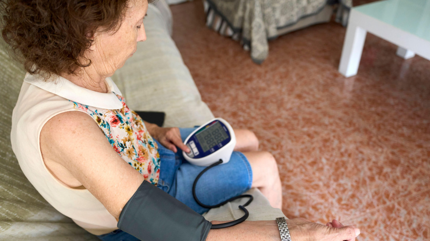 Mujer jubilada midiendo su presión arterial en casa