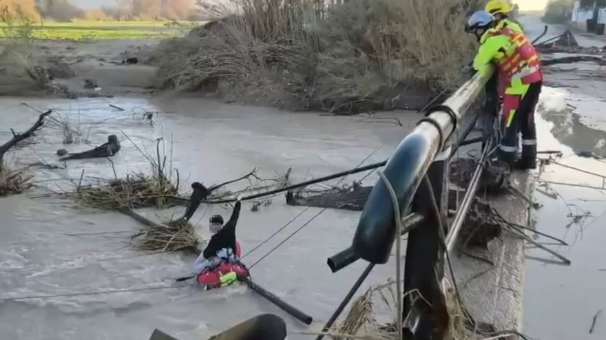 Rescate de los bomberos a la persona atrapada en el turismo caído al río.