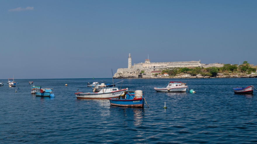 Impresionante vista del malecón de La Habana con barcos de pesca y la colina al fondo.
