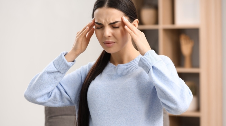 Pregnant young woman suffering from headache indoors