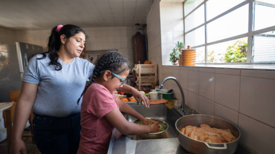 Latin American mother teaching her daughter to cook dinner at home - lifestyle concept