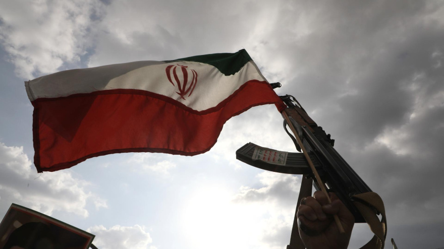 Un partidario hutí sostiene un arma y ondea una bandera iraní durante una protesta contra los ataques estadounidenses e israelíes contra Irán, en Saná, Yemen.