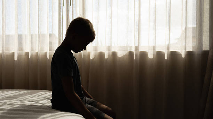 Sad little boy crying sitting at home in bed