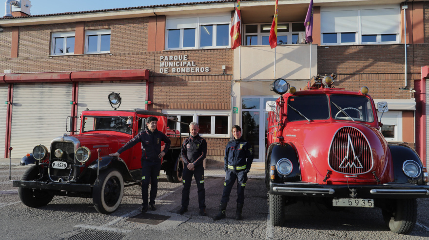 El jefe del parque de bomberos de Palencia, Javier Villena (C), el sargento Abel Allende (I) y la bombera Isabel Villán junto a los dos camiones antiguos conocidos como el Abuelo y la Abuela