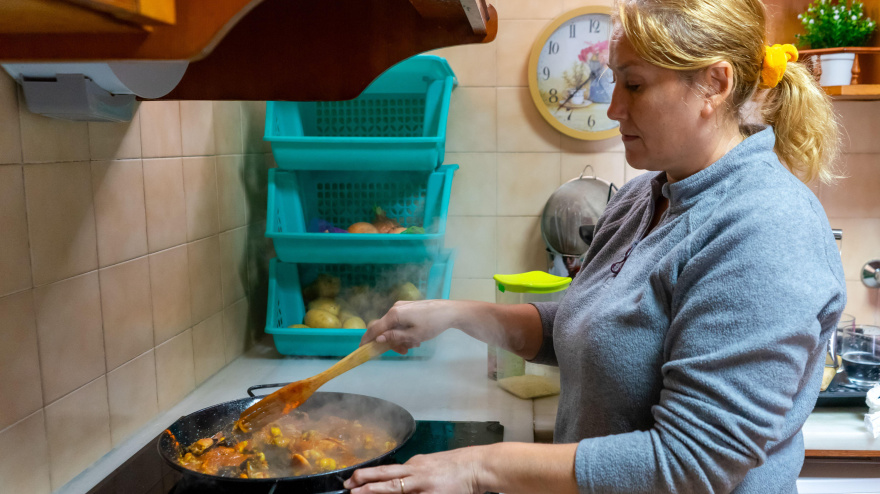 Una mujer cocina paella en una vitrocerámica