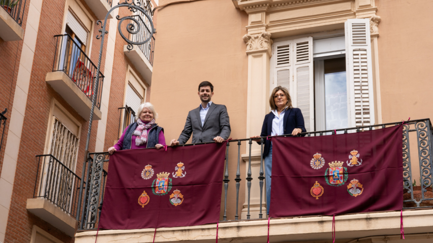 Mujeres cofrades junto al concejal muestran las banderolas
