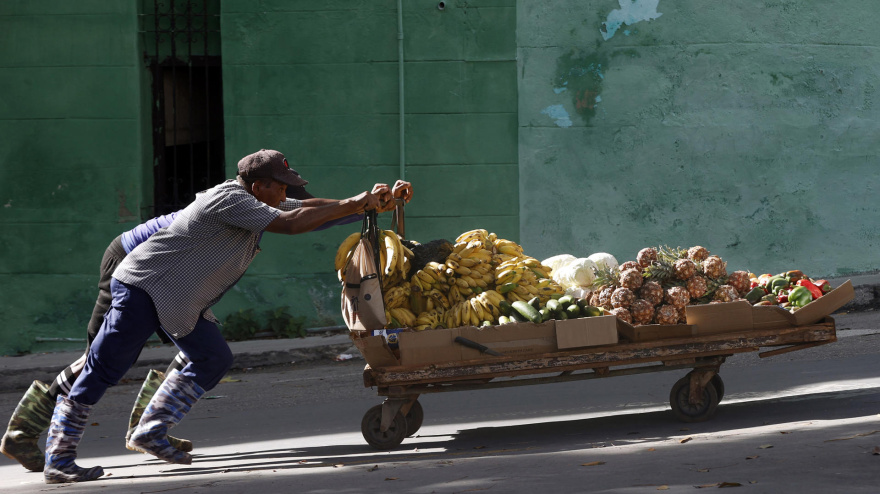 Personas empujan una carretilla con frutas por una calle este lunes, en La Habana, (Cuba)