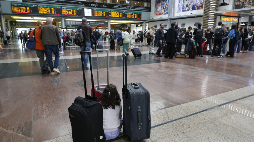 Una niña aguarda junto al equipaje de su familia en la Estación María Zambrano de Málaga