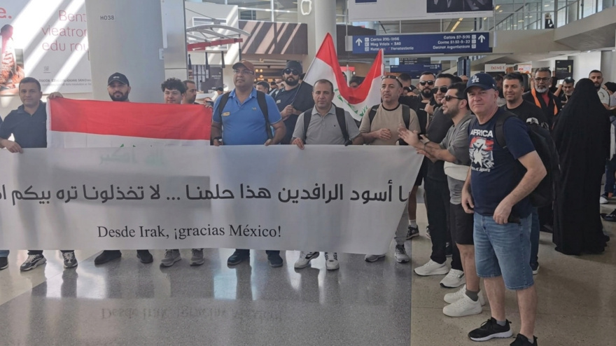 Aficionados de la selección de Iraq sostienen una pancarta en el aeropuerto de Dallas