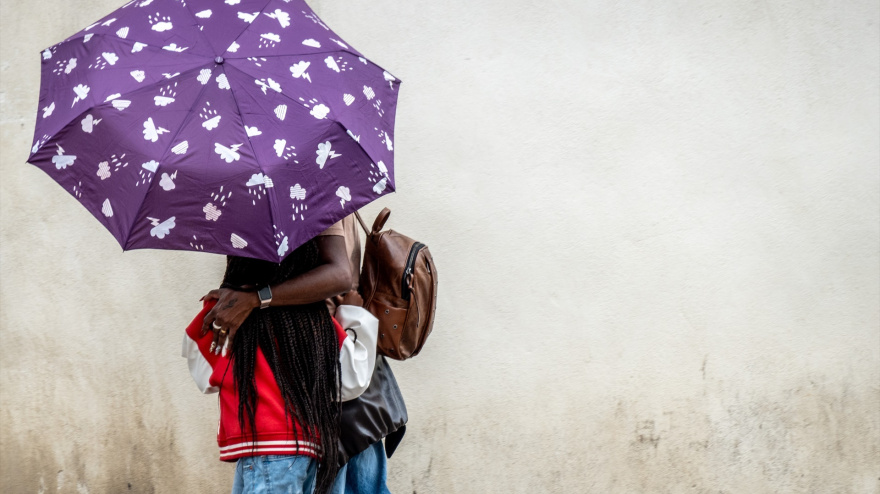Turistas con paraguas por el centro de Sevilla durante la llegada de una nueva borrasca que trae polvo en suspensión