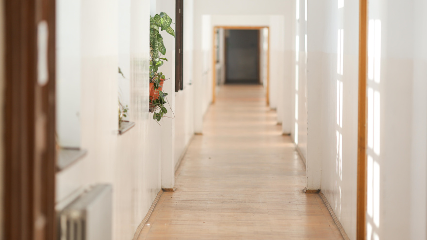 Un largo pasillo vacío, en un edificio antiguo con paredes blancas recién pintadas y suelos de parqué