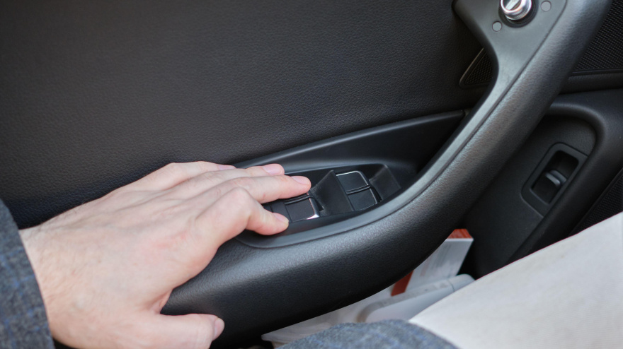La mano presiona un botón para ajustar las ventanas de la puerta.