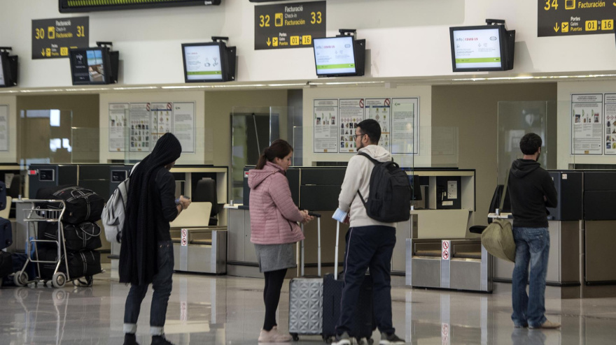 Pasajeros que viajan desde Menorca dirección a Barcelona esperan en uno de los mostradores del Aeropuerto de Menorca